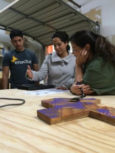 Ana Patterson (Enactus faculty sponsor), Gabriel Castillo (Enactus Student VP for Projects), and Stella (COI wood shop manager) discuss logo options for Beeyond Designs. Photo by Darcy Force, used by permission.