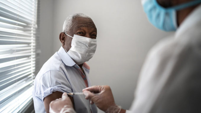 Nurse applying vaccine on patient's arm using face mask Nurse applying vaccine on patient's arm using face mask