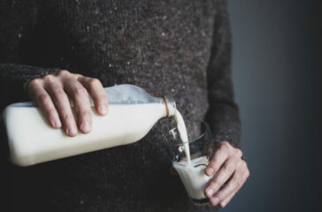 young man in dark wool sweater pouring milk