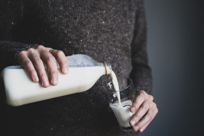 young man in dark wool sweater pouring milk young man in dark wool sweater pouring milk