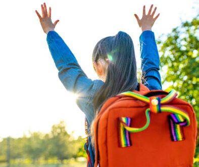 girl student wears backpack outdoors in summer park